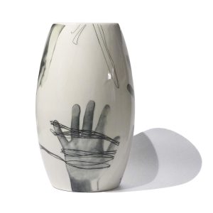 Biały wazon z czarno-białą grafiką dłoni.